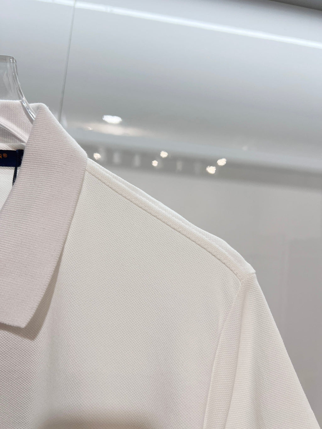 A polo shirt with embroidered letters on the eyes of a golden little monster on the chest