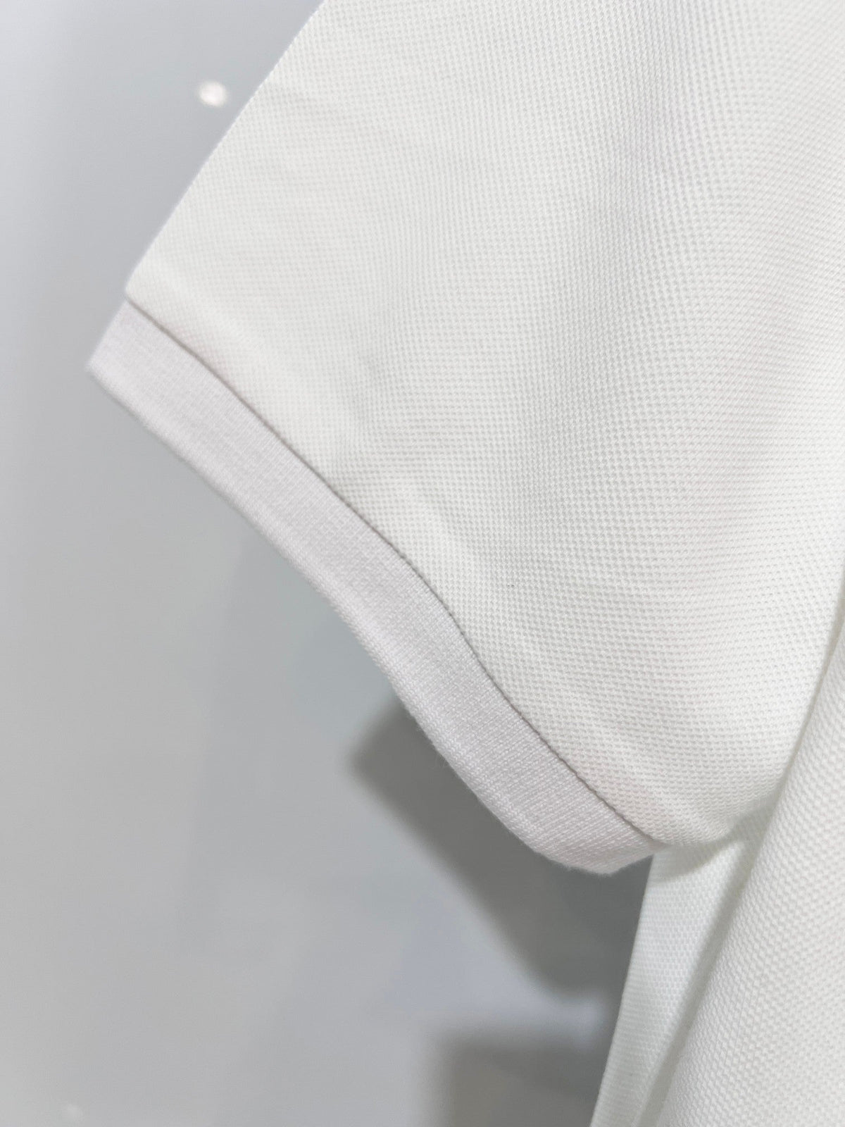 A polo shirt with embroidered letters on the eyes of a golden little monster on the chest