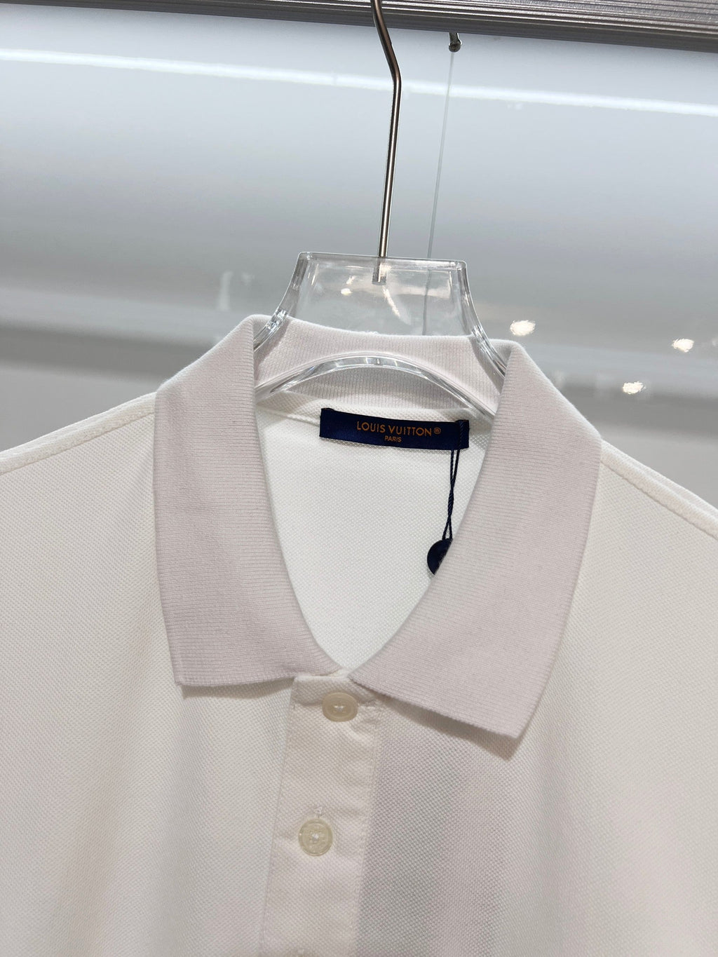 A polo shirt with embroidered letters on the eyes of a golden little monster on the chest