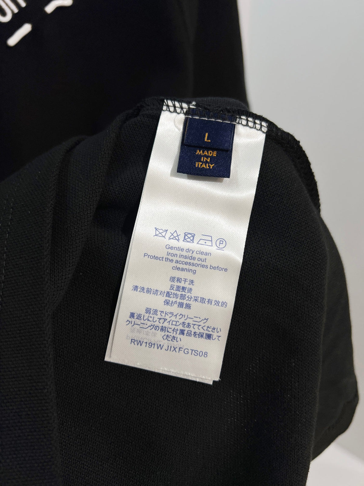 A polo shirt with embroidered letters on the eyes of a golden little monster on the chest