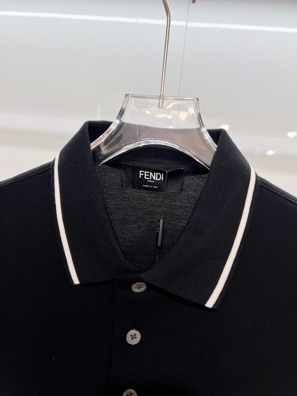 A polo shirt with embroidered letters on the eyes of a golden little monster on the chest